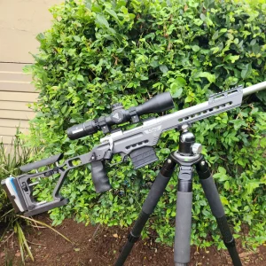 Alpha Elite precision rifle chassis in grey mounted on a heavy-duty tripod for long-range shooting stability.