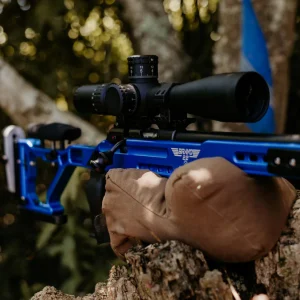 Bravo 22 precision rimfire chassis in vibrant anodized blue resting on a shooting bag during an outdoor match.