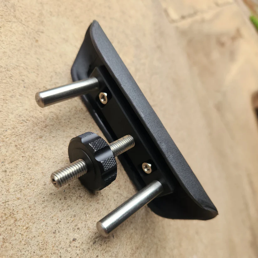 Underside view of a rifle cheek rest displaying the mounting base block, guide posts, and height adjustment mechanism.