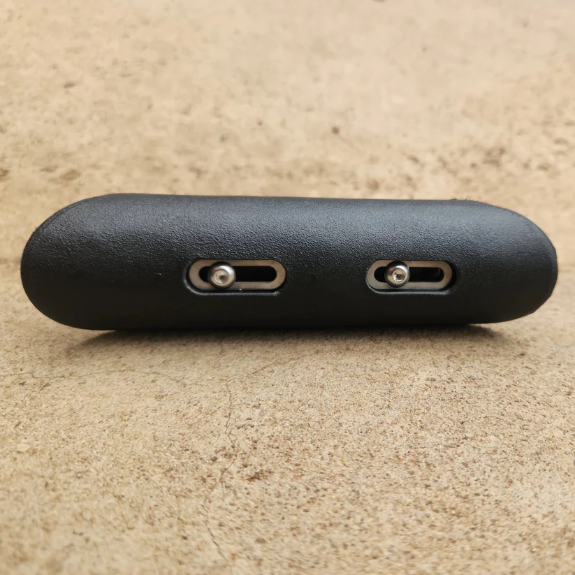 Direct side profile of a black textured cheek pad highlighting two horizontal adjustment slots and Allen screws.